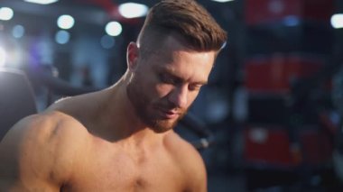 Sporcu su içiyor. Sportif dinlenme. Sakallı adam, bulanık beden eğitimi geçmişiyle ilgili egzersiz yaptıktan sonra ara veriyor. Yakışıklı atletik adam antrenmandan sonra rahatla..