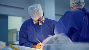Doktor ve asistan bir ameliyat yapar. Klinikte cerrahi aletlerle çalışan tıp uzmanları. Cerrah ameliyathanede profesyonel ameliyat yapıyor..