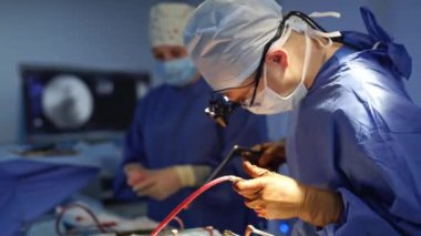 Doktor ve bir hemşire ameliyat yapıyor. Tıbbi üniformalı ve maskeli profesyonel cerrah ameliyathanede cerrahi aletlerle ameliyat yapıyor..