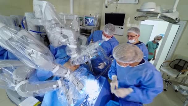 手術室の医療ロボットによる手術 医療専門家がロボットマシンのマシンアームを変える 医師は未来型ロボットマシンの近くで働いている トップビュー — ストック動画