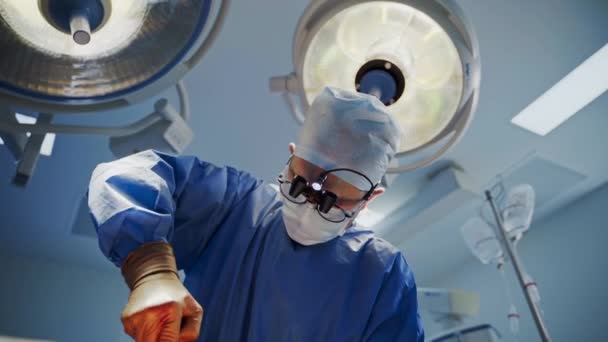 外科ランプの下のマスクの医者の肖像画 手術室で医療機器を使用した手術を行う専門外科医 — ストック動画