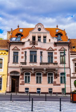 Brasov, Romanya, Transilvanya Seyahati 'nde. Ön planda canlı kırmızı bir yangın musluğu olan bir binanın basit ama göz alıcı görüntüsü..