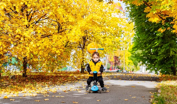 Genç çocuk dışarıda parkta futbol topuyla oynuyordu. Neşeli genç bir çocuk güneşli bir günde parkta futbol topuna vurmaktan mutlu..
