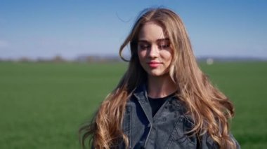 Güzel sarışın dışarıda yürüyor. Bulanık doğa arka planında uzun saçlı çekici genç bir mankenin portresi. Yavaş çekim.