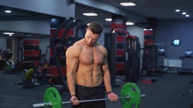 Spor salonunda halter kaldıran güçlü bir sporcu. Ağır bir halterle egzersiz yapan yakışıklı bir adam. Sporcu halterle kuvvet ve dayanıklılık egzersizleri yapıyor. Ağırlık kaldırma.