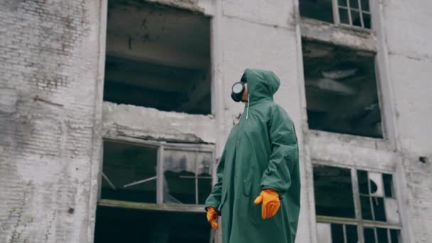屋外でガスマスクや安全スーツを着ている人 ポスト黙示録の場所に立っている呼吸器および保護制服を身に着けている男 ケミカルアタック — ストック動画