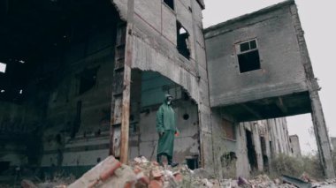 Mahvolmuş yerde takım elbiseli bir kurtulan. Gaz maskeli ve koruyucu giysili bir adam terk edilmiş bir yerde tek başına duruyor. Kıyametten sonraki konsept.