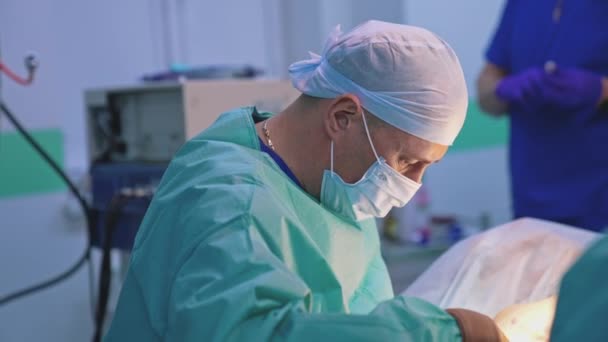 プロの外科医が手術をしています 医師は診療所で医療ツールを使用したプラスチック製の手術を行います プラスチック医師は外科的ハサミを使用しています — ストック動画