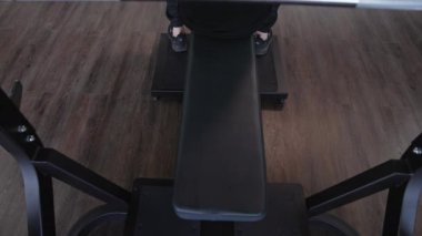Modern spor aletleri üzerinde çalışan yakışıklı bir adam. Genç sporcu spor salonunda bir simülatör üzerinde egzersiz yapmaya başlar. Spor salonunda egzersiz yapan kaslı bir adam. Üst görünüm.