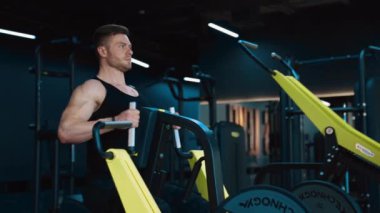 Simülatördeki kaslı sporcu. Vücut geliştirici spor merkezinde modern bir simülatör üzerinde çalışıyor. Spor salonunda spor yapan yakışıklı bir sporcu..