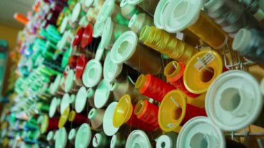 Masanın üzerinde farklı renkte iplik makaraları var. Dikiş endüstrisi için renkli iplik koleksiyonu. Pamuk ipliği olan birçok makaranın arkaplanı.