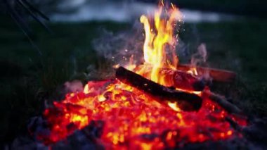 Kıvılcımlarla yanan ateş. Adam akşamları yanan odunları sopayla kırıyor. Kömürde parlayan odun. Koyu arka planda kırmızı kömürler yanıyor. Yakın plan..