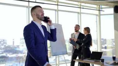 Mutlu iş adamı telefon görüşmesi yapıyor. Ofiste çalışan ortaklar yeni stratejiler geliştiriyor. Şirketteki iş adamları..