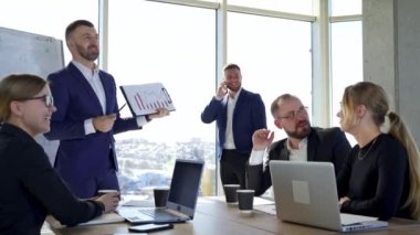Pozitif iş adamları ofiste. Girişimci takımı birlikte iş birliği yapıyor. Erkek lider iş stratejisini meslektaşlarına anlatıyor..