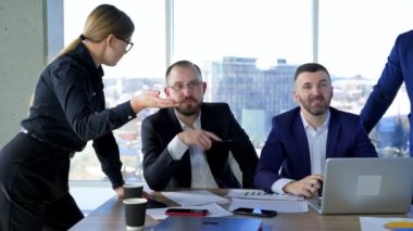 Mutlu iş ortakları ofis merkezinde çalışır. Girişimci grubu pencere arkaplanında şehir görüşü ile sohbet ediyor.