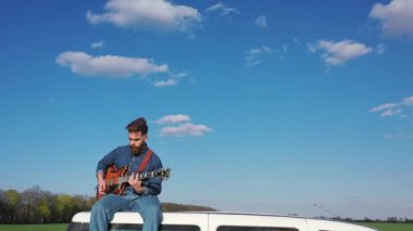 Genç hippi dışarıda gitar çalıyor. Sakallı adam hareket halindeki bir arabada oturuyor ve gitar çalıyor. Gezgin gökyüzü arka planında müzik aleti çalıyor.