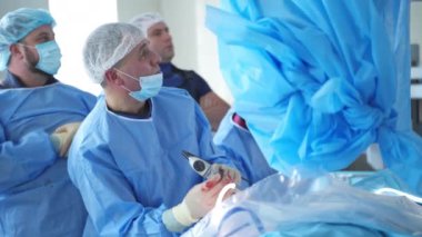 Klinikte ameliyat. Tıbbi üniformalı bir grup doktor bir ameliyat yapıp dümdüz bakıyorlar. Tıbbi ve hayat kurtarma kavramı.
