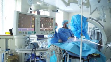 Tıbbi monitörler ameliyat sırasında çalışıyor. Klinikte ameliyat yapan doktorların arka planında hastanın durumunu gösteriyor..