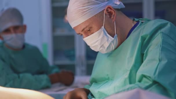 プロの外科医が手術をしています 診療所の患者に手術を行っている間 外科用具で作業する医療マスクの医師 — ストック動画