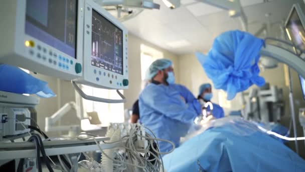 有现代医疗设备的手术室 进行手术的外科医生背景下显示病人心跳的监测器 — 图库视频影像