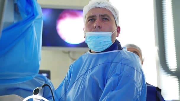 医生用手术器械做手术 穿着蓝色医疗制服的专业外科医生负责做手术 并在监测过程中进行监测 — 图库视频影像