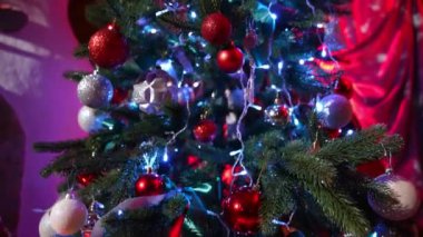 Işıkları ve süslemeleri olan Noel ağacı. Evdeki yeşil bir köknar ağacında parlak noel baloları ve kurdeleler. Yeni yıl atmosferi.