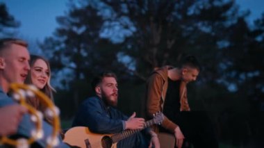 Mutlu arkadaşlar geceyi kamp ateşinin yanında geçirirler. Gençler gece şarkı söyleyip gitar çalıyorlar. Doğa arasında dostça vakit geçirmek..