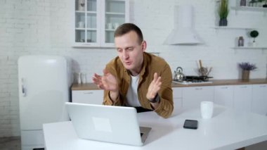 Genç iş adamı evde video görüşmesi yapıyor. Öğrenci mutfak arka planında kablosuz bir dizüstü bilgisayarın önünde konuşuyor. Uzak görev.