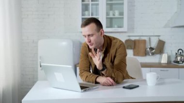 Freelancer mutfakta dizüstü bilgisayar üzerinde çalışıyor. Yakışıklı adam evde mutfak masasında otururken bir video görüşmesi yapıyor. Öğrenci çevrimiçi çalışıyor.