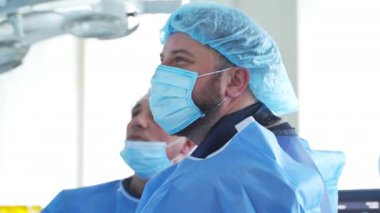 Ameliyathanede maskeli doktorlar var. Tıbbi üniforma ve maske giyen bir cerrahın yan görüntüsü klinikte işe yarıyor. Profil görünümü.