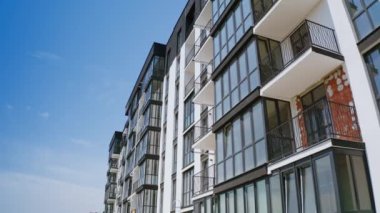 Çok katlı binanın modern cephesi. Mavi gökyüzüne karşı siyah beyaz renkte yeni bir apartman. Drone görünümü.