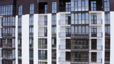 Siyah ve beyaz apartman blokları. Şehirde camlı balkonları olan modern çok katlı bir binanın ön manzarası. Güzel yeni konutlar.