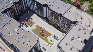 Yeni yüksek katlı evler. Şehirde çocuk parkı ve park yeri olan modern bir yerleşim yeri. Üst hava görüntüsü.