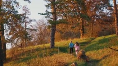 Ormanda koşuşturan arkadaşlar. Genç adam ve kız sabah doğada koşuyorlar. Gençler gün batımında koşar. Arka görünüm.