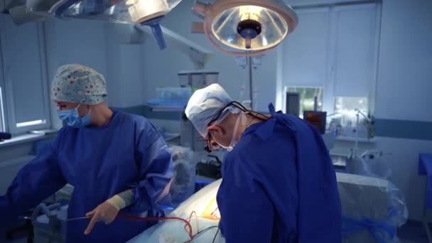クリニックでの神経外科手術 専門医と看護師が手術台の患者に手術を行っています トップビュー — ストック動画