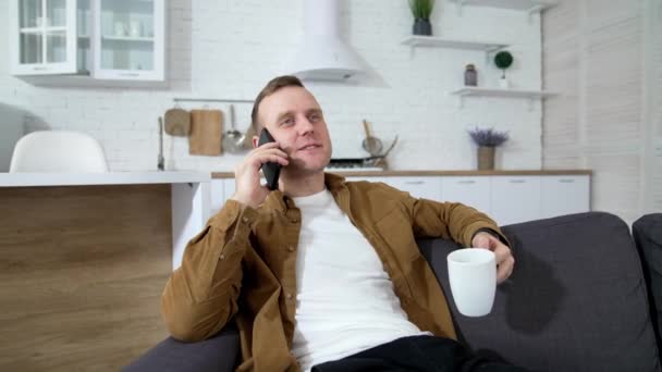 Joven Hablando Por Teléfono Cocina Guy Está Sentado Sofá Con — Vídeos de Stock