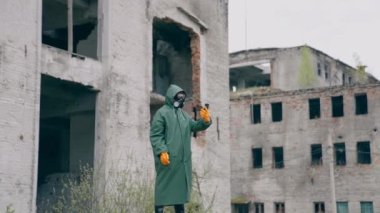 Koruyucu giysili bir insan ve terk edilmiş bir yerde gaz maskesi. Hayatta kalan kişi harabe bir şehirde dururken elinde cep telefonu tutuyor. Nükleer savaştan sonra kıyamet sonrası dünya.
