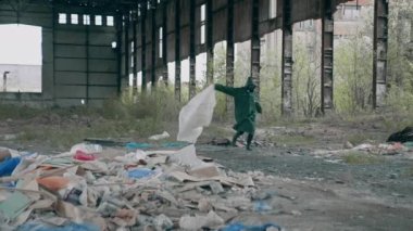 Terk edilmiş bir yerde hayatta kalan biri. Koruyucu giysili ve gaz maskeli insanlar çöp arka planındaki harabe binada çılgınca koşuyorlar..