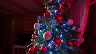 Işıkları ve kurdeleleri olan güzel bir Noel ağacı. Oturma odasındaki şöminenin yanında Noel toplarıyla süslenmiş köknar ağacı..