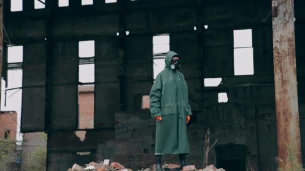 破壊された建物の背景の安全スーツの生態学者 ガスマスクや保護服の人は 化学攻撃後に危険な場所に立っています — ストック動画