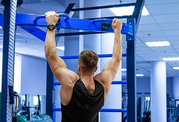 Man Performing Pull Ups in Gym. A man effortlessly performs pull ups in a well-equipped gym.