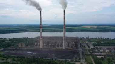 Dumanı tüten fabrika binası. Nehir kenarındaki sanayi bölgesinde. Üretimden çıkan zararlı duman doğadaki atmosferi kirletir. Hava görünümü.