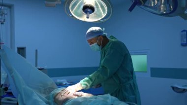 Doktor liposuction ameliyatı yapıyor. Hastanedeki hastanın karnına estetik ameliyat yapan bir cerrah. Ameliyathanede mavi ışık..