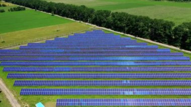 Yeşil doğa arasındaki uzun fotovoltaik güneş panelleri. Yenilikçi güneş enerjisi istasyonunun üzerinden güneş ışığında uçmak. Yeni enerji kaynağı. Hava görünümü.