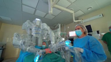 Robot kollu modern tıbbi ekipmanlar. Klinikte minimal invaziv robotik cerrahi. Modern tıbbın olduğu ameliyathane. Doktorlar tıbbi robotların çalışmalarını kontrol ediyorlar..