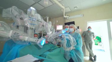 Minimum invaziv ameliyat sırasında kollarını hareket ettiren robot makine. Ameliyat odasında gelecekteki cerrahi yenilikler. Doktorlar robot cerrahisini inceliyor..