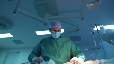 Abdominoplasti yapan üniformalı bir cerrah. Ameliyathanede bir hastanın karnından cerrahi müdahaleyle yağ alınması..