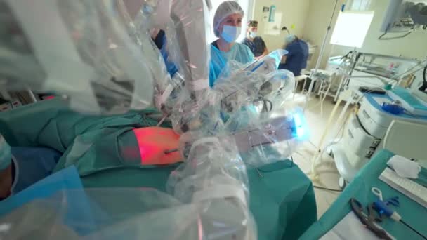 医療ロボットによる外科手術 診療所の患者さんの手術中のロボット機器 ロボット手術中の患者の腹の赤い光 — ストック動画