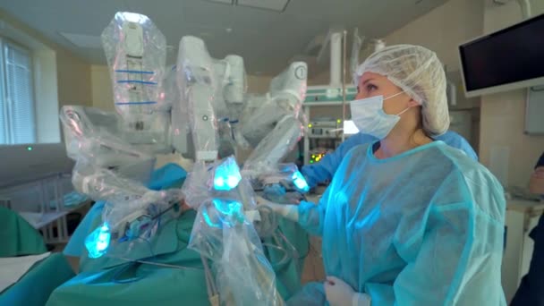 ロボットを含む医療活動 クリニックでの運転中の医療ロボット 女性外科医がロボット手術中にスクリーンを見る — ストック動画