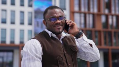 Siyahi derili iş adamı dışarıda bir telefon görüşmesi yapıyor. Belediye binasında telefonu olan Afro-Amerikan bir adamın portresi..